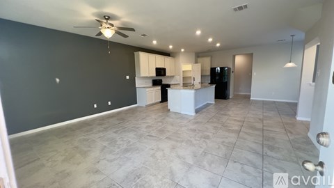 A spacious living room with a kitchen in the background.