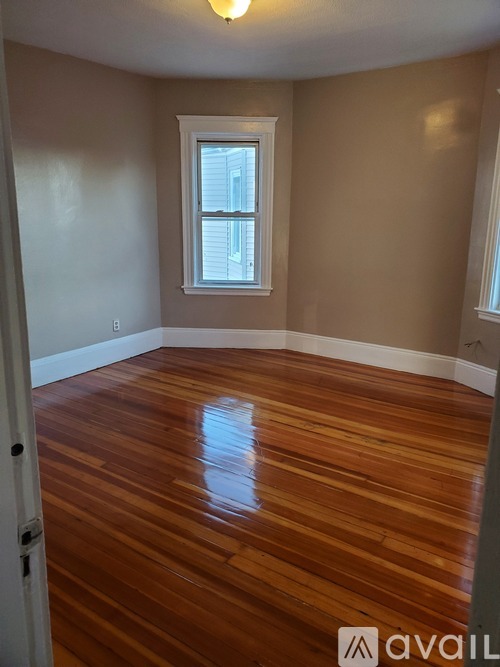 A room with wooden flooring and a window.