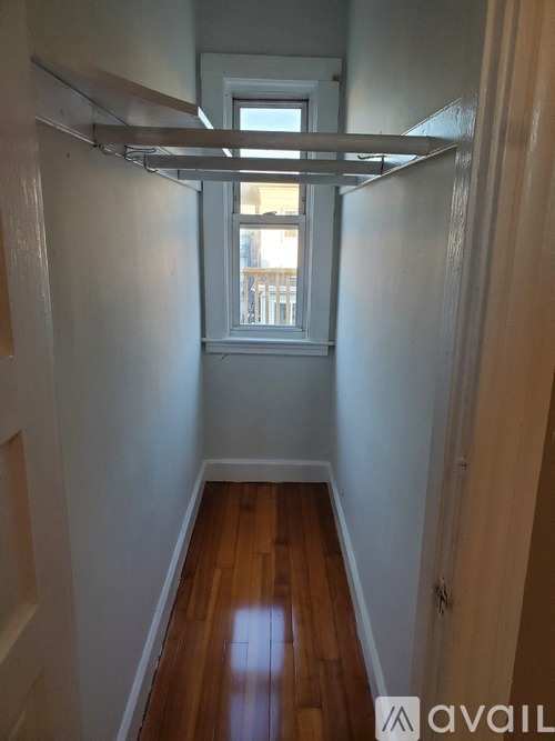 A long hallway with a window and a white door.