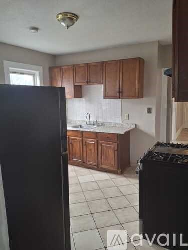 A kitchen with a black refrigerator and wooden cabinets.