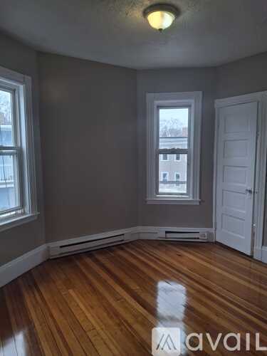 A room with wooden floors and a window overlooking a building.