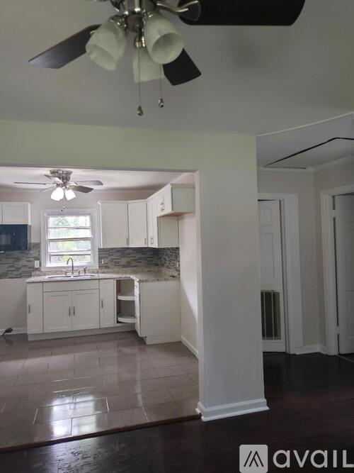 A kitchen with white cabinets and a ceiling fan.
