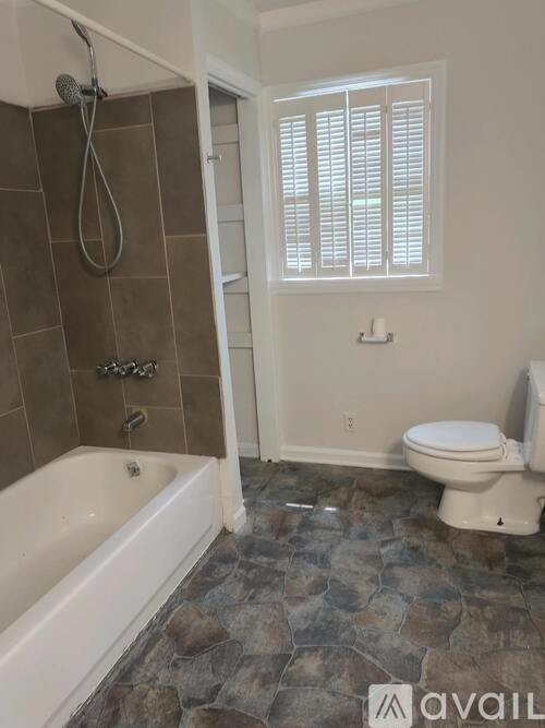 A bathroom with a tub, toilet, and window.