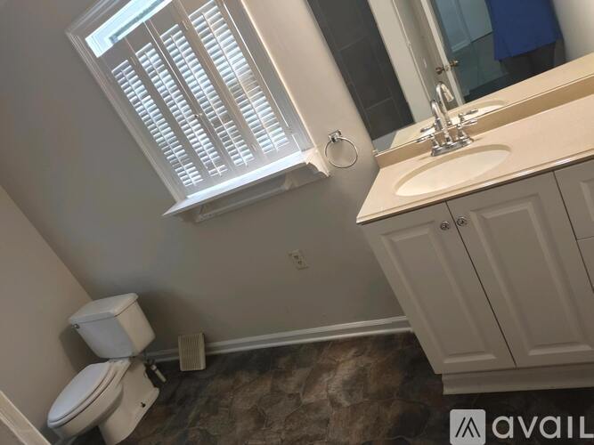 A bathroom with a toilet, sink, and a window.