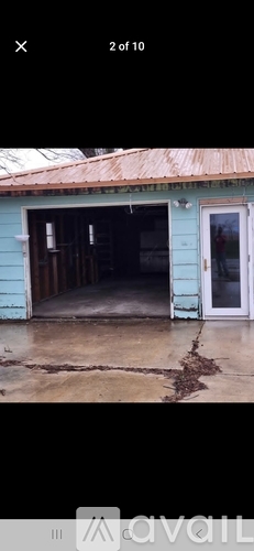 A blue building with a white door and a cracked ground.