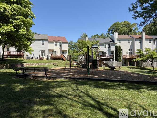 A sunny day at a park with a playground and benches.