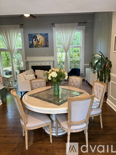 A dining room with a table surrounded by chairs and a painting on the wall.