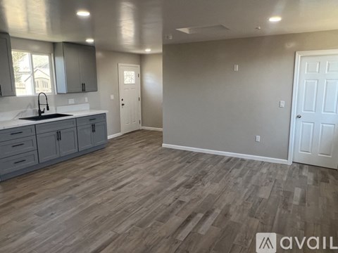 A kitchen with grey cabinets and a white sink.