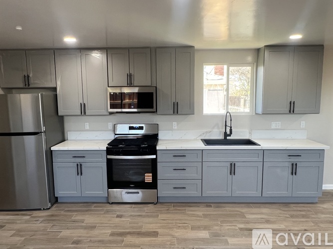 A kitchen with grey cabinets and a stainless steel refrigerator.
