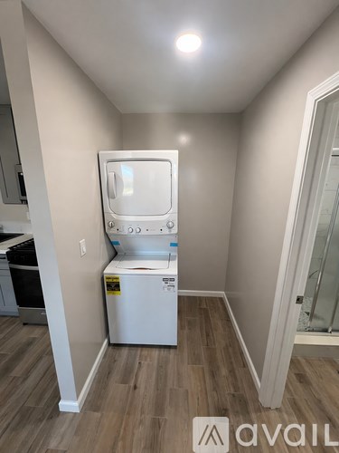 A small white dishwasher is in a kitchen with wood flooring.