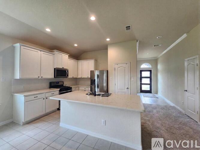A kitchen with white cabinets and a countertop is available for rent.