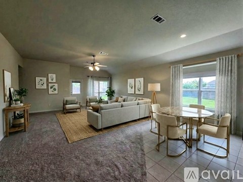 A living room with a grey couch, a dining table with chairs, and a rug on the floor.