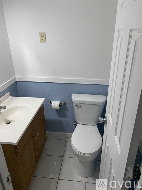 A white toilet in a bathroom with a white sink and a white door.
