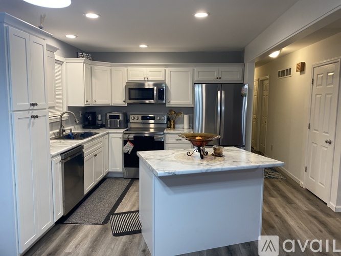 A kitchen with white cabinets and a marble island.