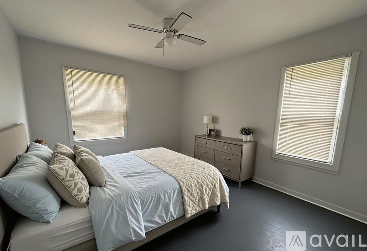 A bedroom with a bed, nightstand, and window with blinds.