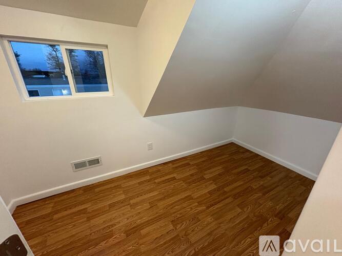 A room with wooden flooring and a window.