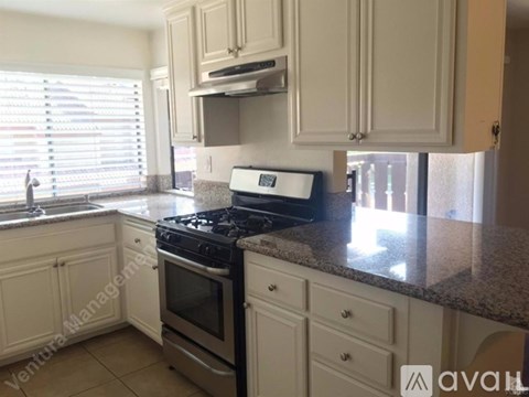 A kitchen with white cabinets and a granite countertop.