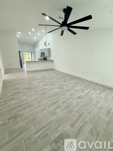 A spacious room with a fan and wooden flooring.