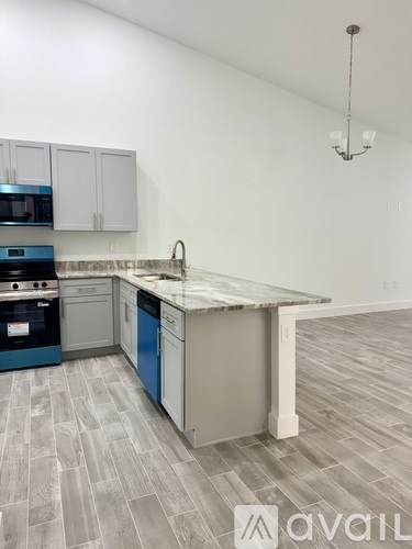 A kitchen with a blue dishwasher and a grey island.