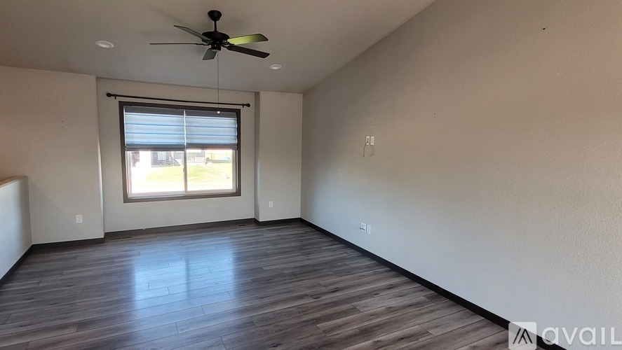 A room with a ceiling fan and a window with blinds.