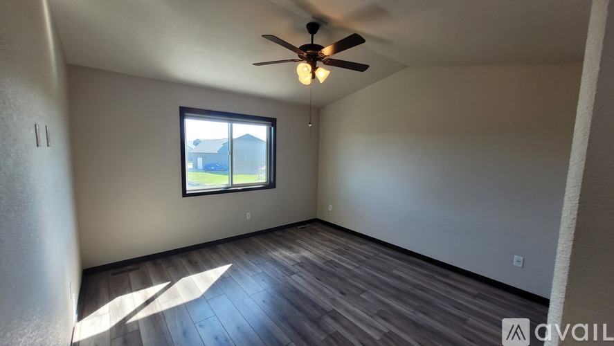 A room with a ceiling fan and a window letting in sunlight.