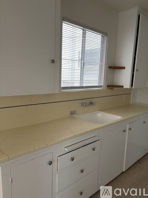 A white kitchen with a sink and a window.