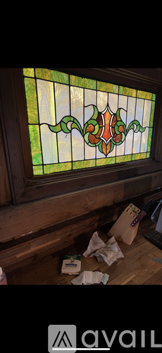 A stained glass window with a floral design is in the corner of a room.