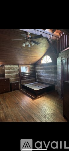A wooden room with a bed and a ceiling fan.