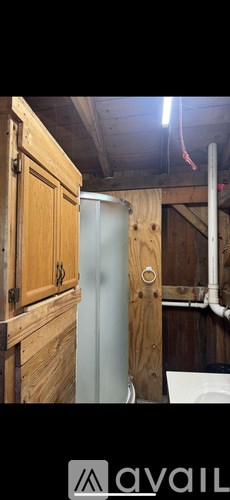 A wooden cabinet with a glass door is next to a white toilet in a small bathroom.