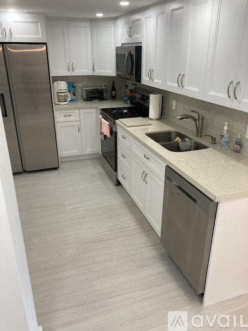 A kitchen with white cabinets and a stainless steel refrigerator.