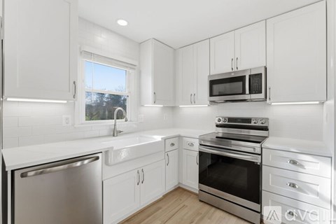 A white kitchen with a stainless steel dishwasher and oven.