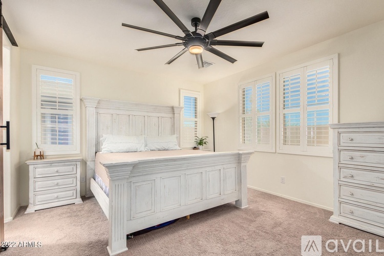 A bedroom with a bed, dresser, and ceiling fan.