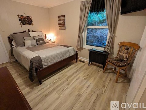 A bedroom with a bed, chair, and window.