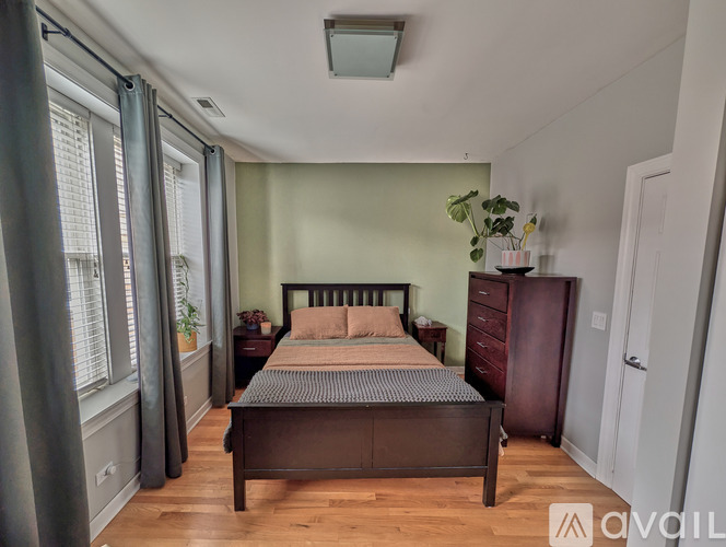 A bedroom with a bed, nightstand, and a plant on the windowsill.
