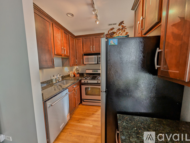 A kitchen with wooden cabinets and a black refrigerator.