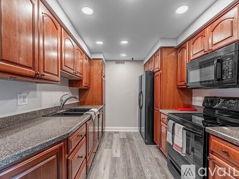 A kitchen with wooden cabinets and black appliances.