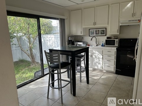 A kitchen with a table and chairs in front of a sliding glass door.