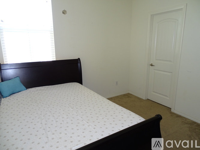 A bedroom with a bed, a door, and a window.