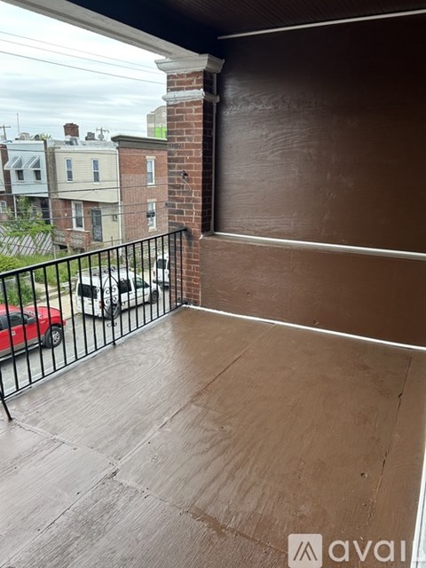 A balcony with a metal railing and a view of a street with cars and buildings.