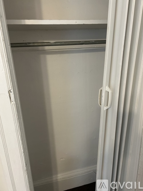 A white closet with a hanging rod and a white door.