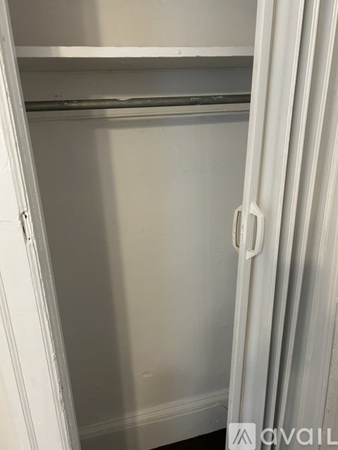 A white closet with a hanging rod and a white door.