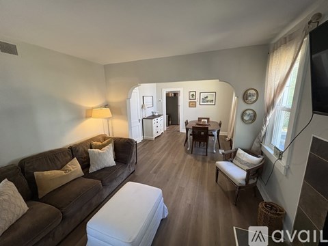 A living room with a brown couch and a white ottoman.
