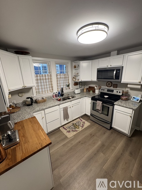 A kitchen with white cabinets and a wooden island.