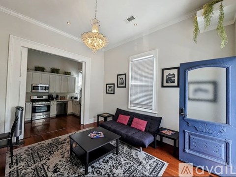 A living room with a black couch and a chandelier.