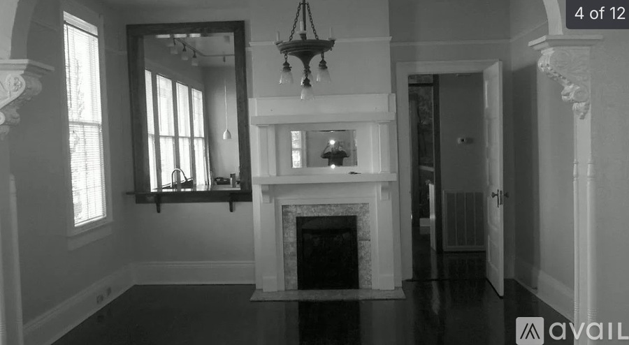 A black and white image of a room with a fireplace and a chandelier.