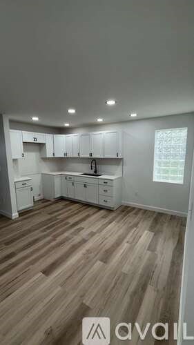 A kitchen with wooden floors and white cabinets is available for rent.