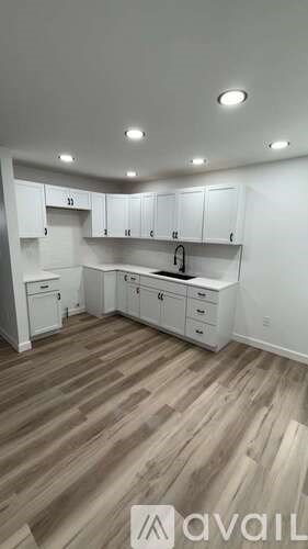 A kitchen with white cabinets and wooden flooring.