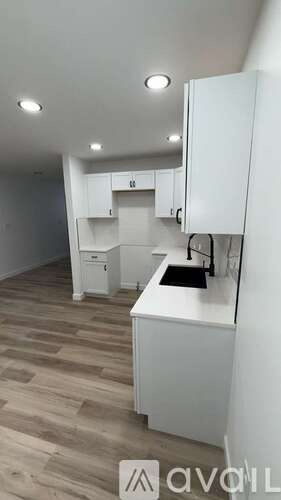 A kitchen with white cabinets and a wooden floor.