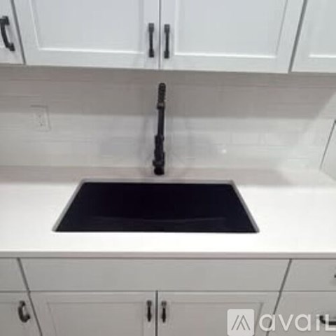 A kitchen with white cabinets and a wooden floor.
