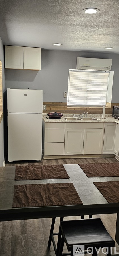 A kitchen with a white refrigerator and brown tiles on the floor.